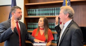 J. Collin Sims being sworn in by Louisiana Supreme Court Justice William J. Crain, his wife Elizabeth holds the bible.